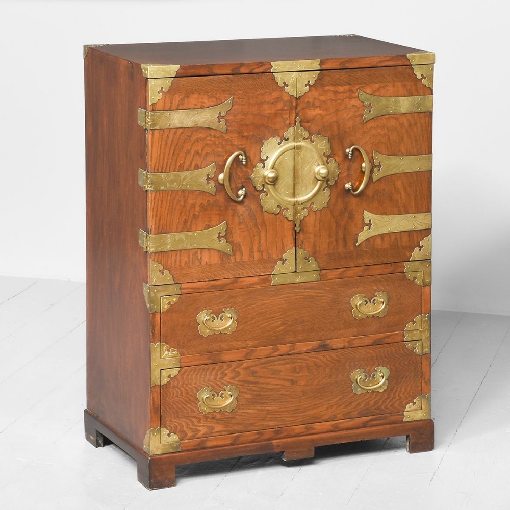 A Korean wooden side cabinet featuring two upper doors with a central circular brass lockplate and two lower drawers with brass pull handles.