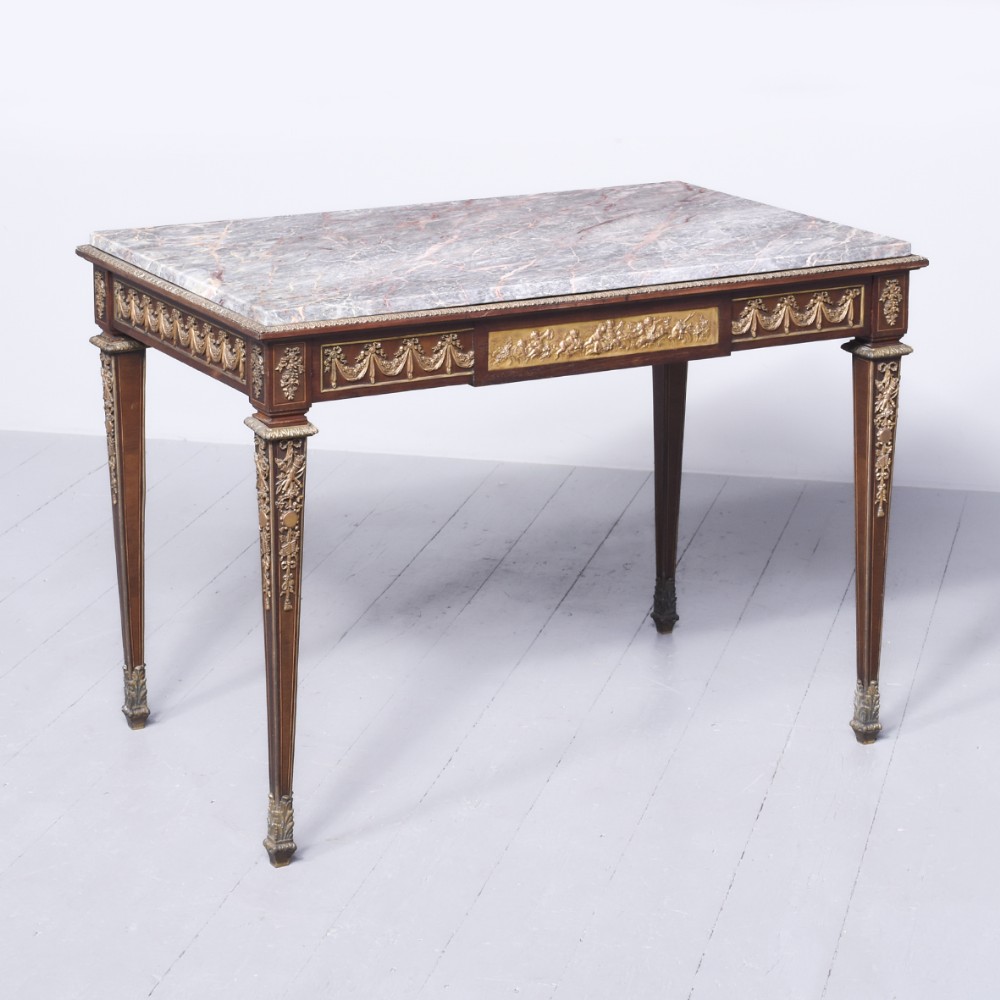 A rectangular French mahogany centre table featuring a grey marble top, tapered fluted legs, and intricate gilt-bronze ormolu mounts.