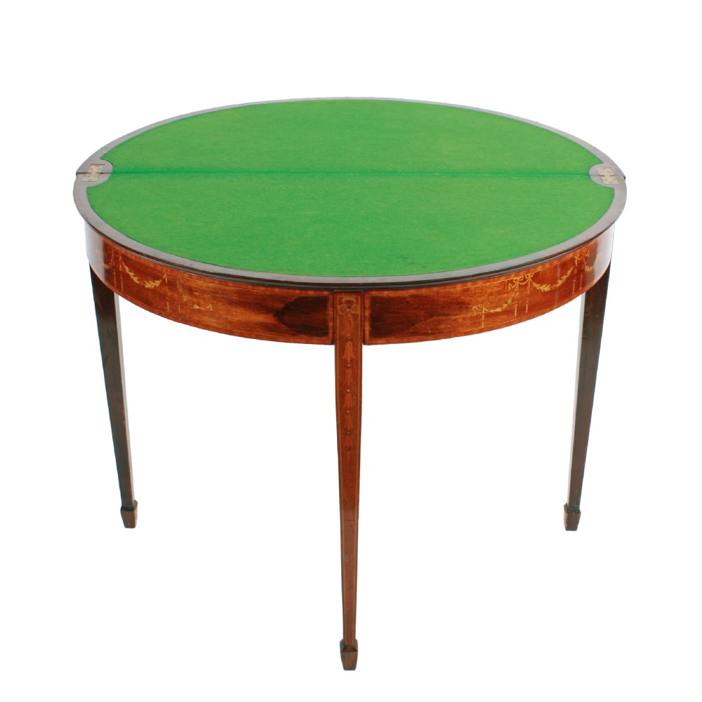 A semi-circular mahogany card table featuring floral marquetry inlay on the top and apron, supported by four square tapered legs. View VII