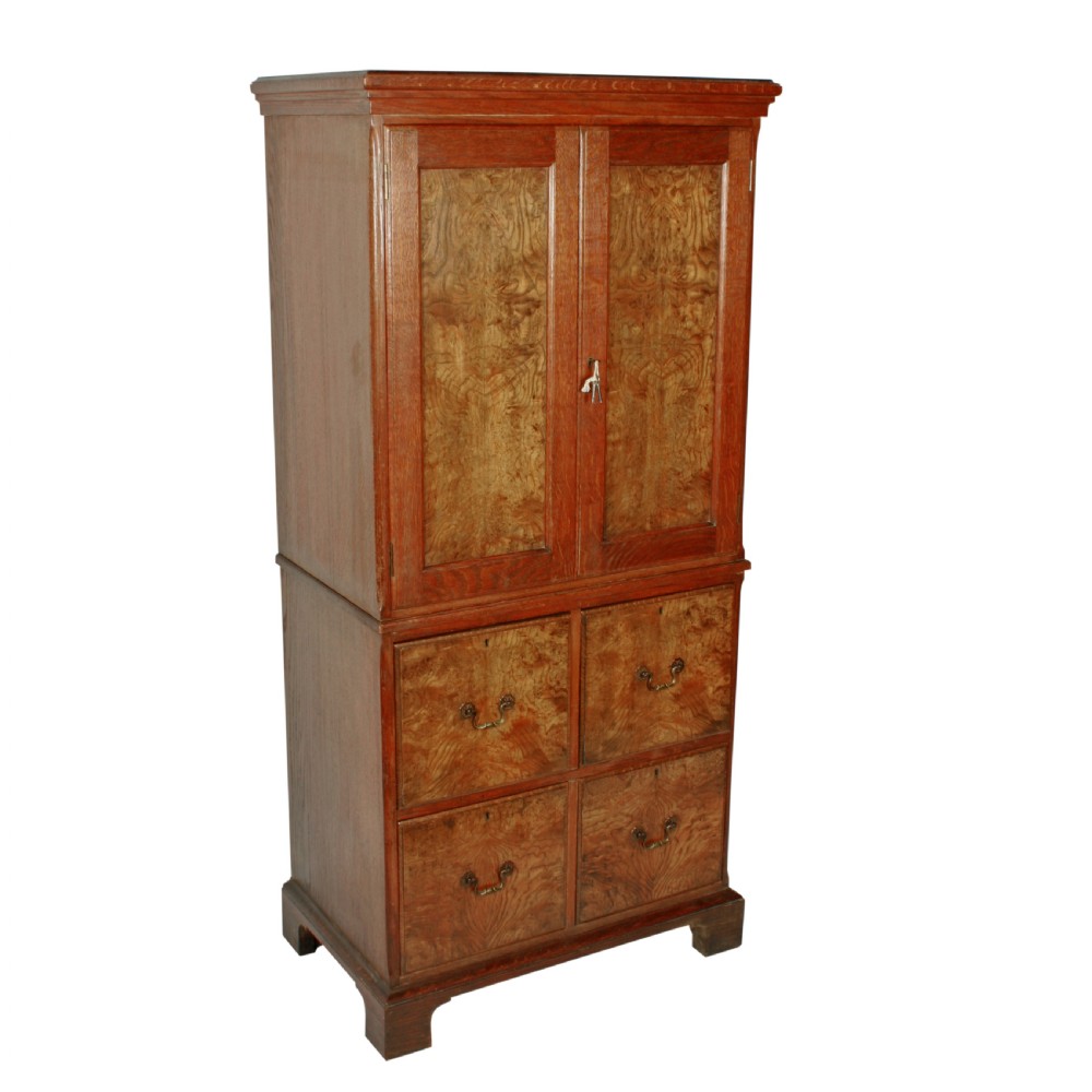 A tall two-section wooden cabinet featuring upper panelled doors with figured veneer and four lower drawers with brass handles. View II