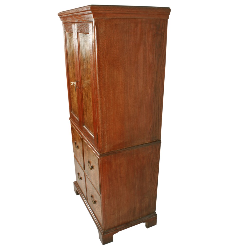 A tall two-section wooden cabinet featuring upper panelled doors with figured veneer and four lower drawers with brass handles. View X