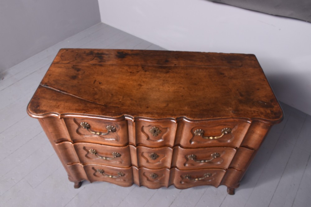 An 18th-century French walnut commode featuring three drawers with moulded fronts, brass swing handles, and a shaped apron on short legs. View IX