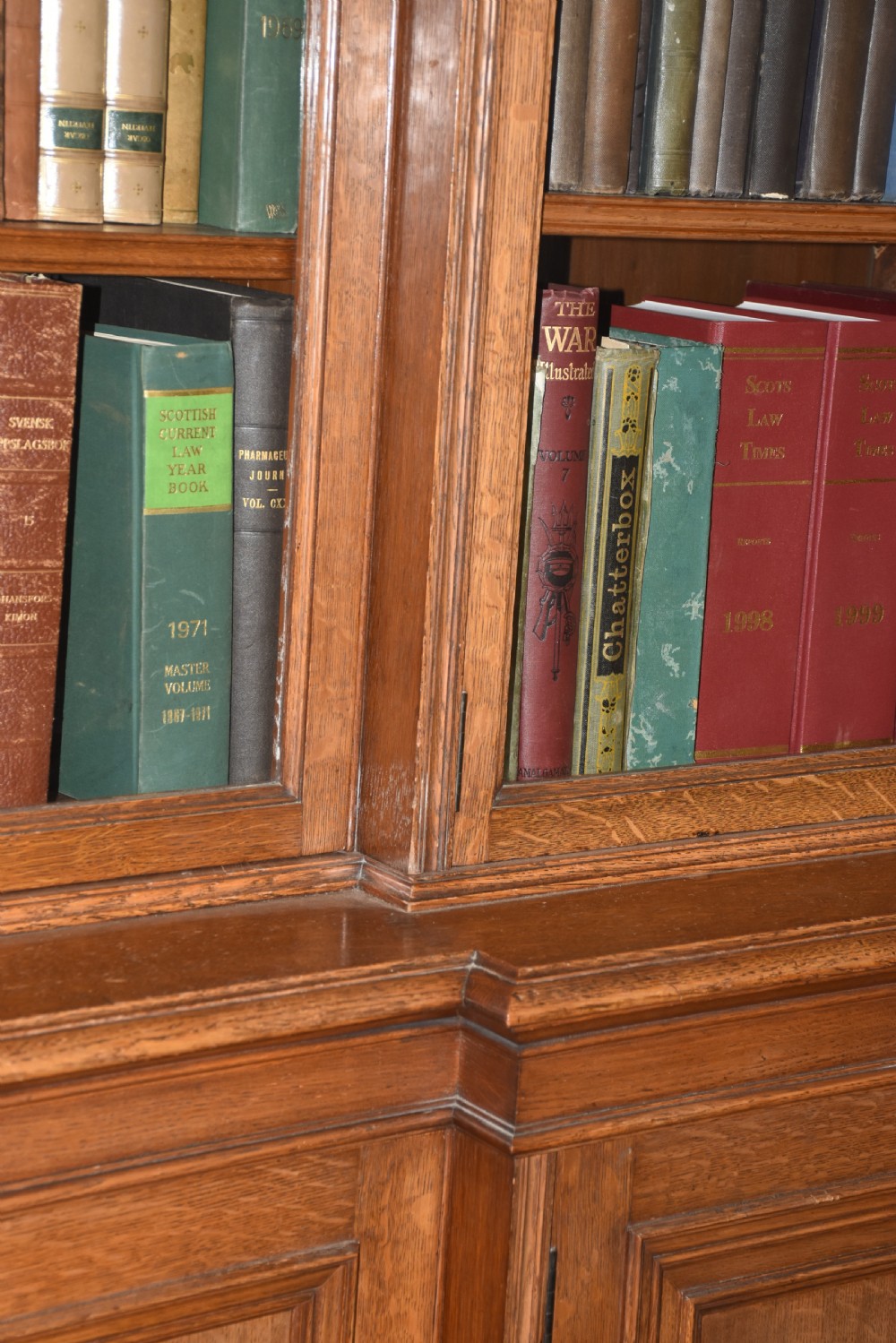 A large antique carved oak breakfront bookcase featuring glazed upper doors above solid panelled lower cupboards. View II