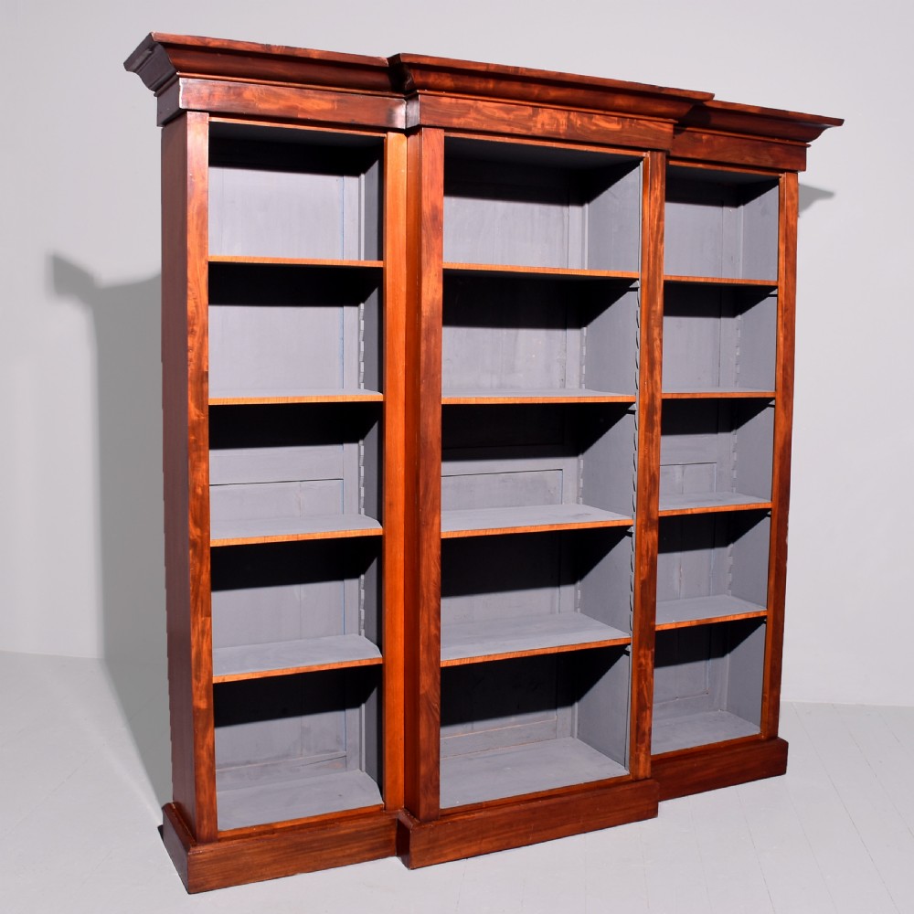 An early Victorian mahogany breakfront open bookcase featuring three sections with adjustable shelving and a grey painted interior.