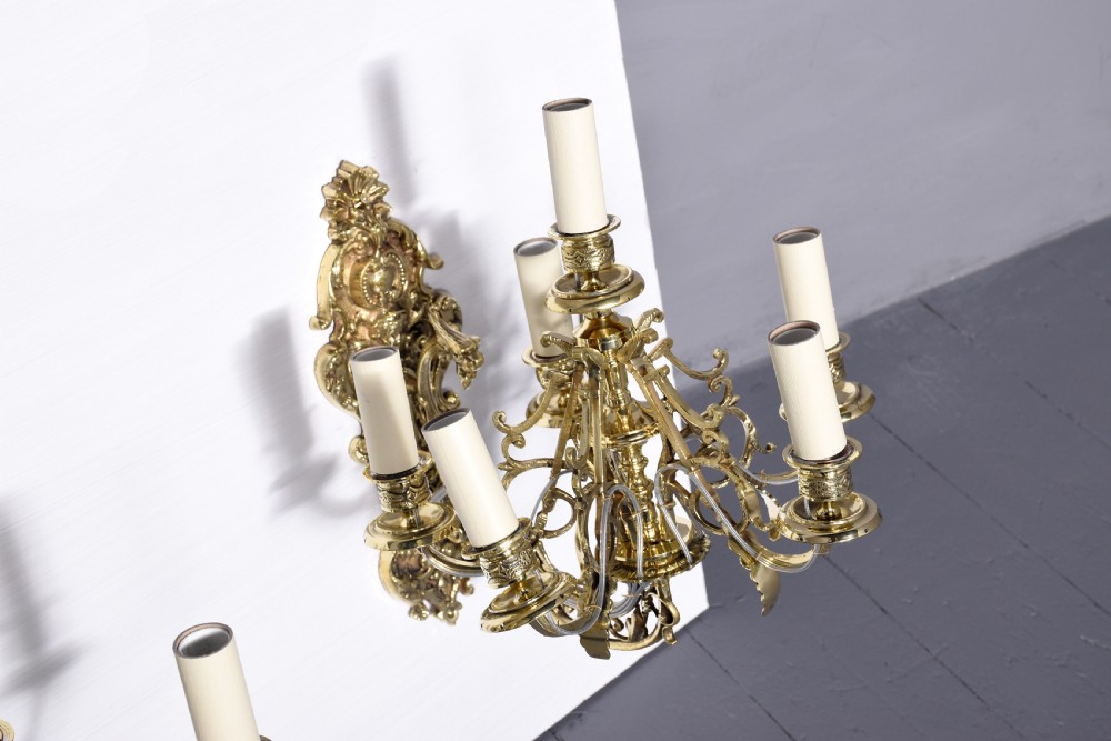 A pair of cast brass Rococo-style five-light wall sconces featuring scrollwork backplates and sweeping candle arms. View VI