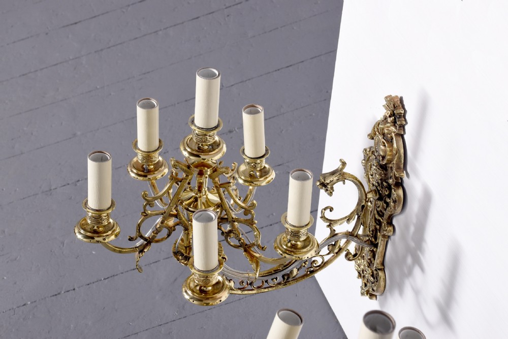 A pair of cast brass Rococo-style five-light wall sconces featuring scrollwork backplates and sweeping candle arms. View VII