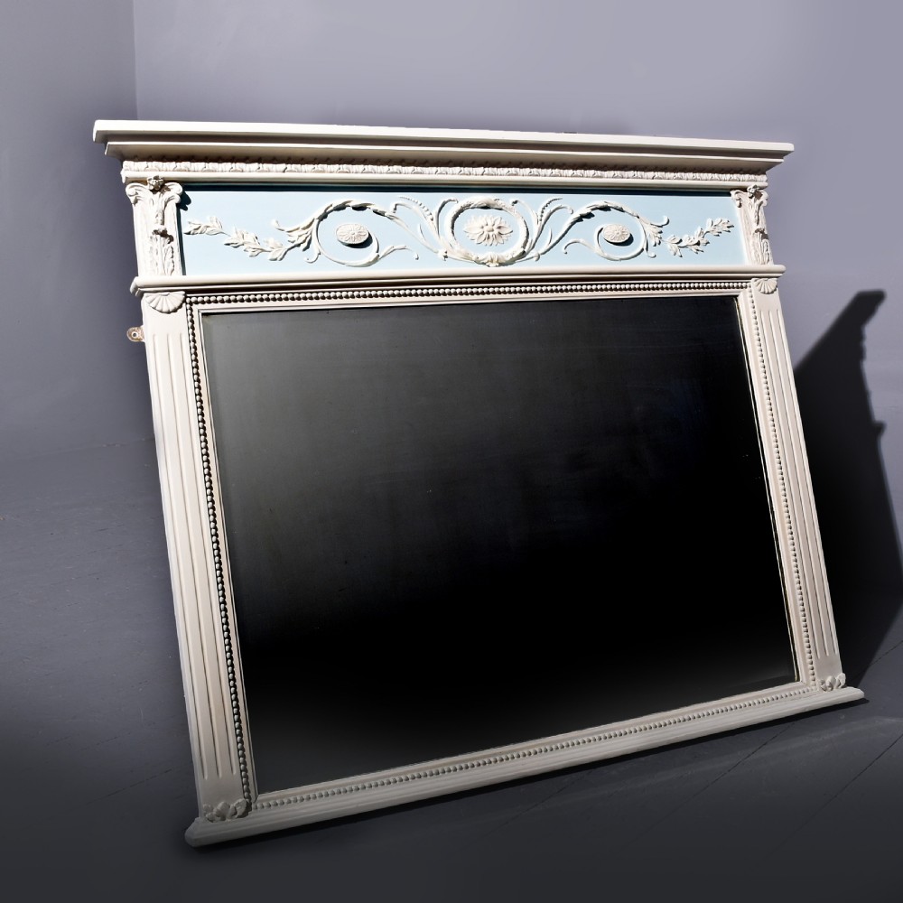 A Neoclassical painted overmantel mirror with an off-white fluted frame, beaded trim, and a light blue frieze featuring plaster swags and floral medallion details.