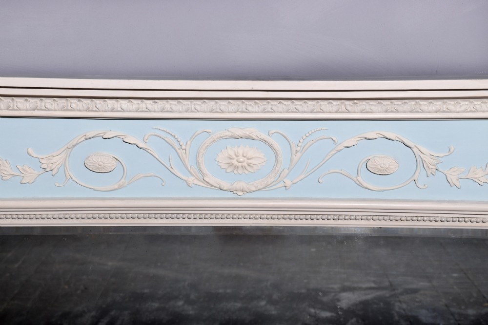 A Neoclassical painted overmantel mirror with an off-white fluted frame, beaded trim, and a light blue frieze featuring plaster swags and floral medallion details. View III