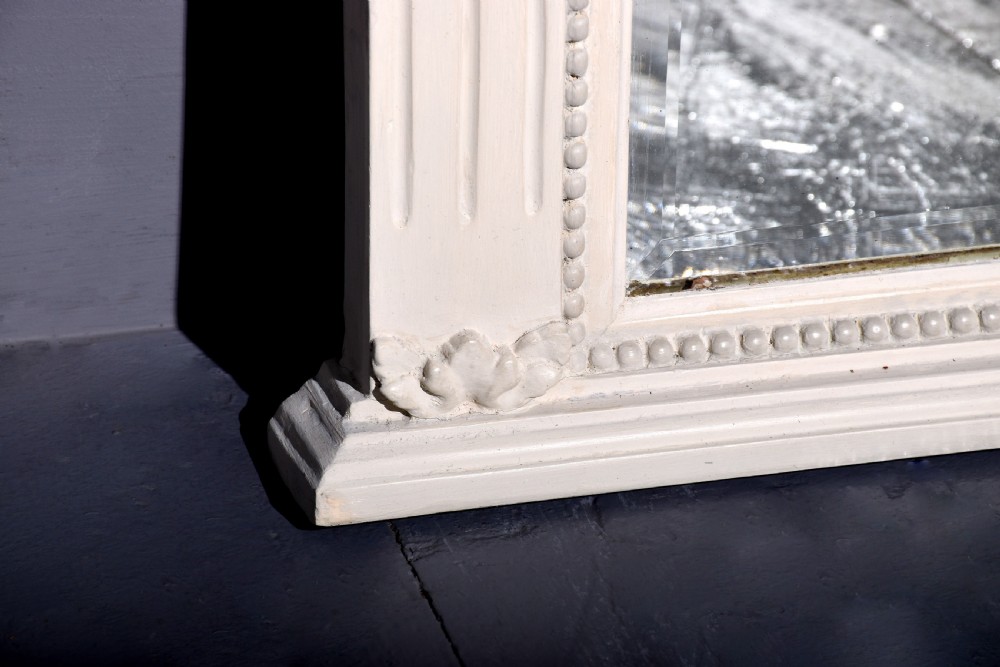 A Neoclassical painted overmantel mirror with an off-white fluted frame, beaded trim, and a light blue frieze featuring plaster swags and floral medallion details. View V