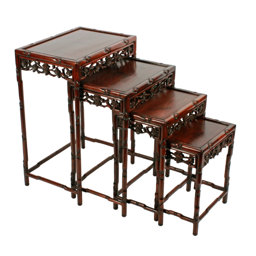 A set of four graduated dark brown Chinese hardwood nesting tables featuring faux-bamboo carved legs and pierced openwork aprons.