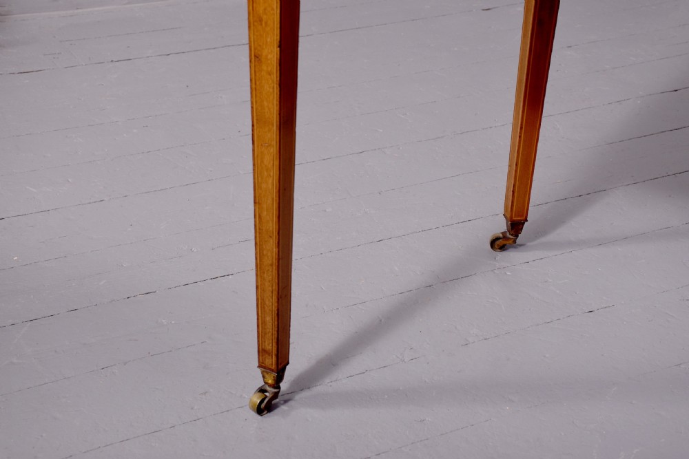 A satinwood Carlton House writing desk featuring a brass gallery railing, U-shaped superstructure with small drawers, leather writing surface, and square tapered legs on castors. View XI