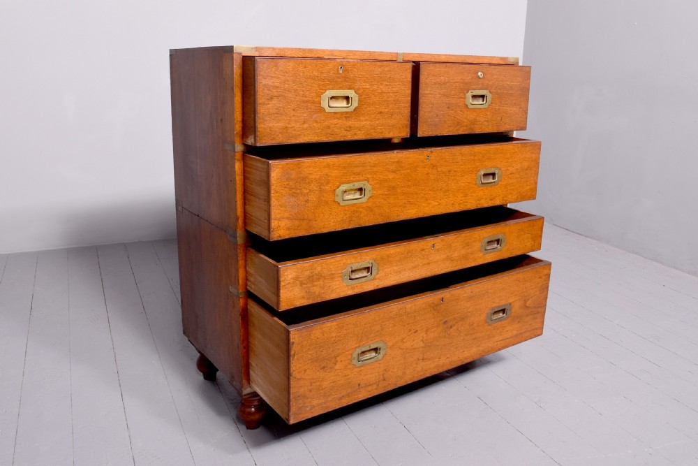 A Victorian mahogany two-part military campaign chest with flush brass handles, protective brass corner brackets, and turned legs. View II