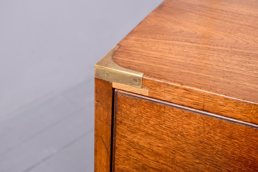 A Victorian mahogany two-part military campaign chest with flush brass handles, protective brass corner brackets, and turned legs. View VI