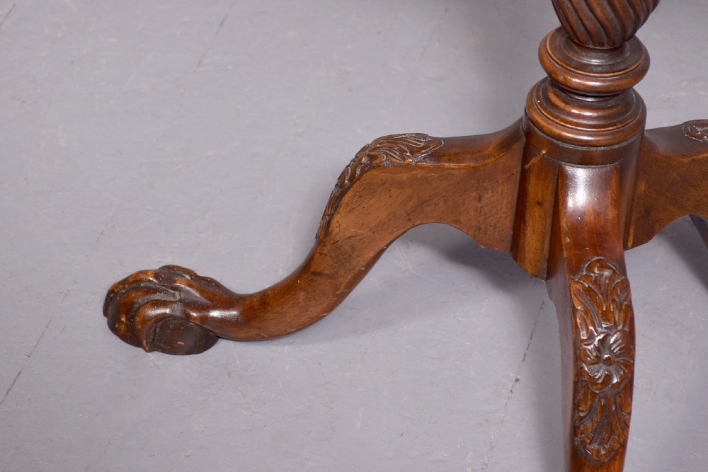 A round mahogany occasional table featuring a raised spindle gallery top, turned central pedestal stem, and cabriole tripod legs ending in claw and ball feet. View V