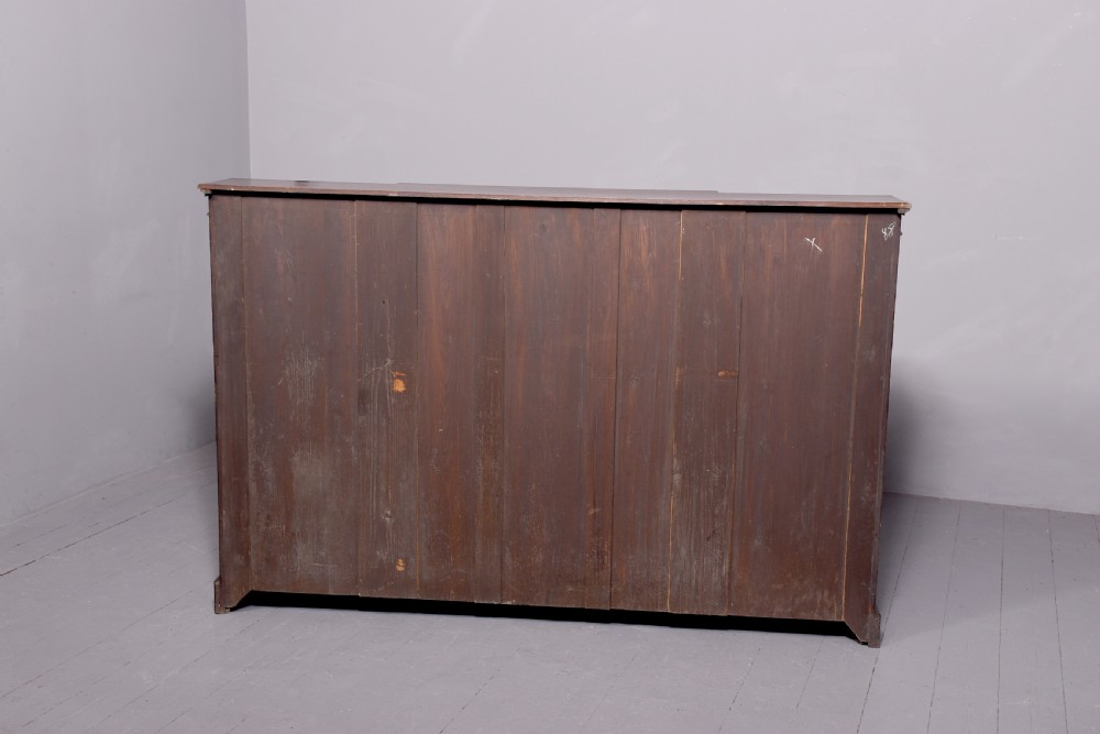 A large dark oak breakfront open bookcase filled with rows of leather-bound books. View II