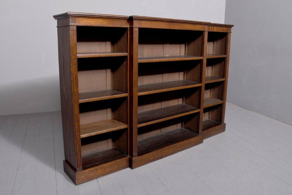 A large dark oak breakfront open bookcase filled with rows of leather-bound books. View III