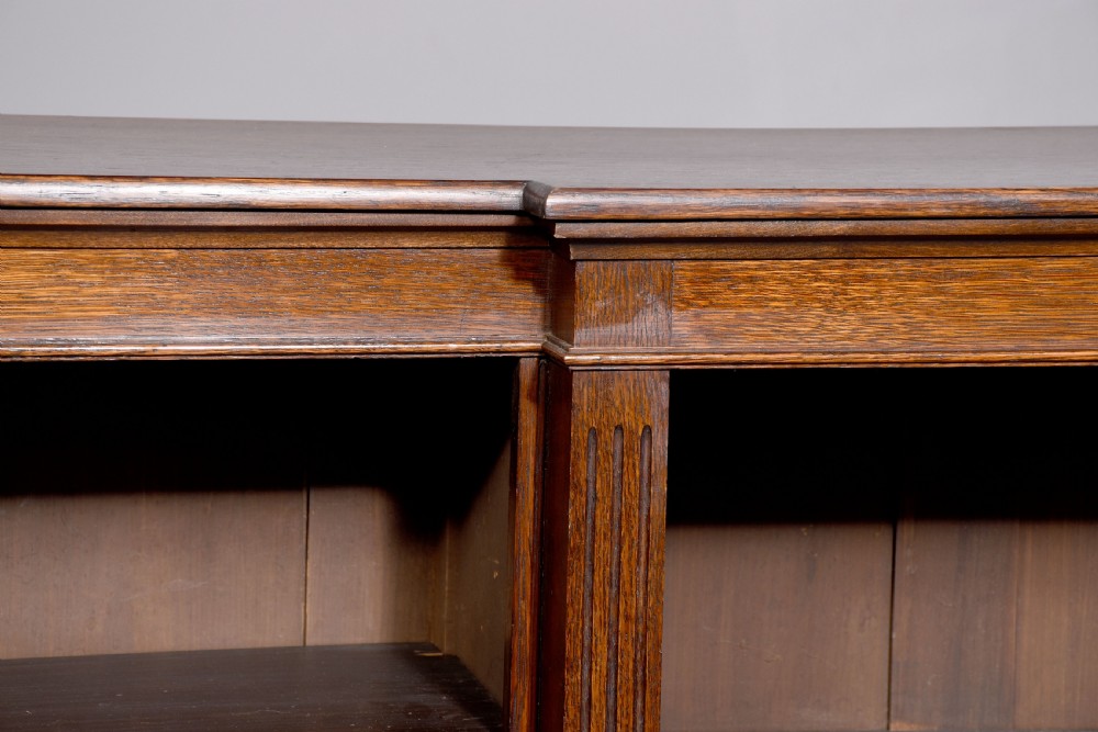 A large dark oak breakfront open bookcase filled with rows of leather-bound books. View V