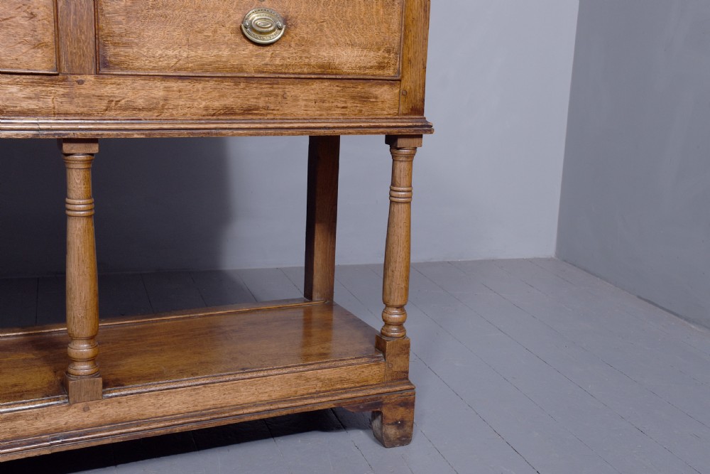 A George III two-part oak dresser featuring an open three-shelf plate rack with iron hooks above two drawers and an open potboard base. View III