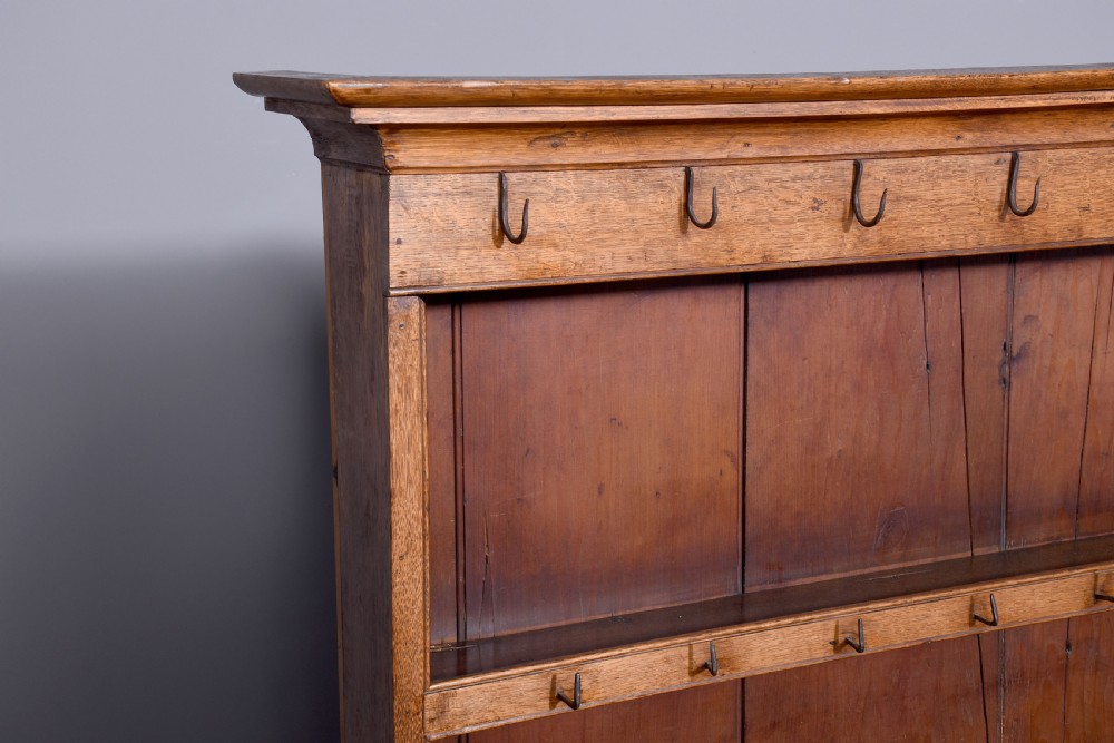 A George III two-part oak dresser featuring an open three-shelf plate rack with iron hooks above two drawers and an open potboard base. View VIII
