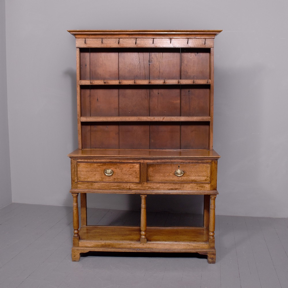 A George III two-part oak dresser featuring an open three-shelf plate rack with iron hooks above two drawers and an open potboard base. View X