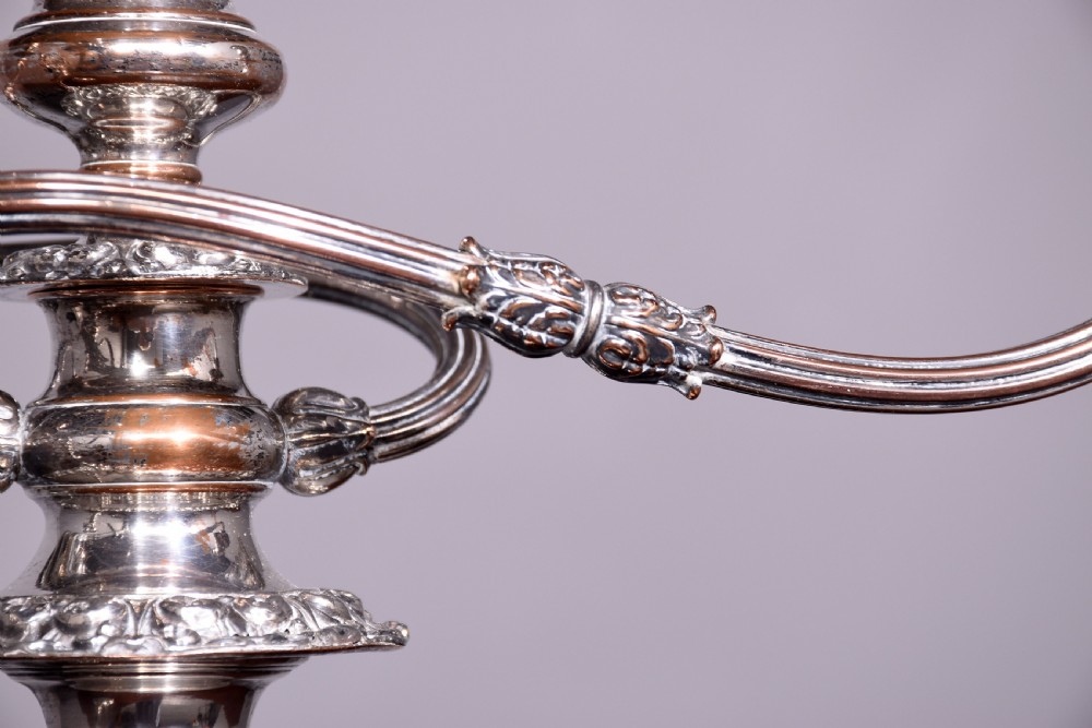A pair of antique silver-plated three-light candelabra featuring circular bases, baluster stems, and curved reeded branches. View V