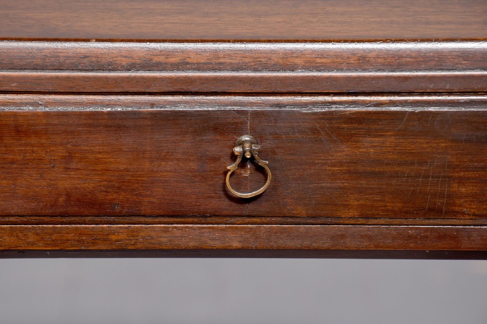 A tall, narrow mahogany side table featuring four straight legs, a single drawer with a central brass ring pull, and a polished wood surface. View III