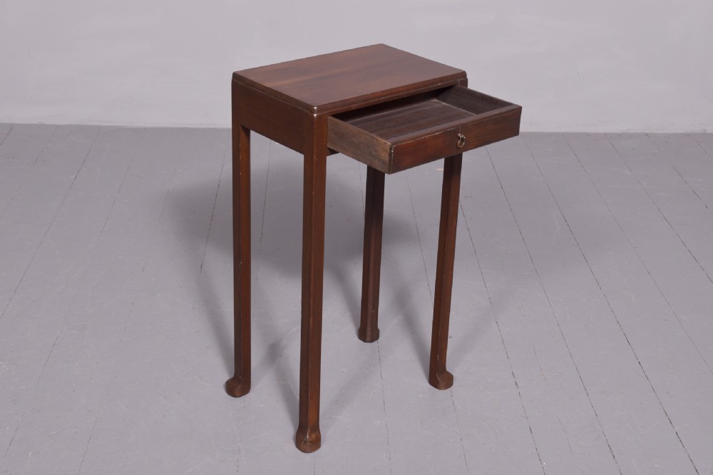 A tall, narrow mahogany side table featuring four straight legs, a single drawer with a central brass ring pull, and a polished wood surface. View IV