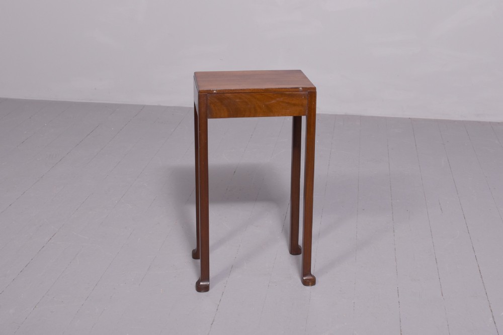 A tall, narrow mahogany side table featuring four straight legs, a single drawer with a central brass ring pull, and a polished wood surface. View VII
