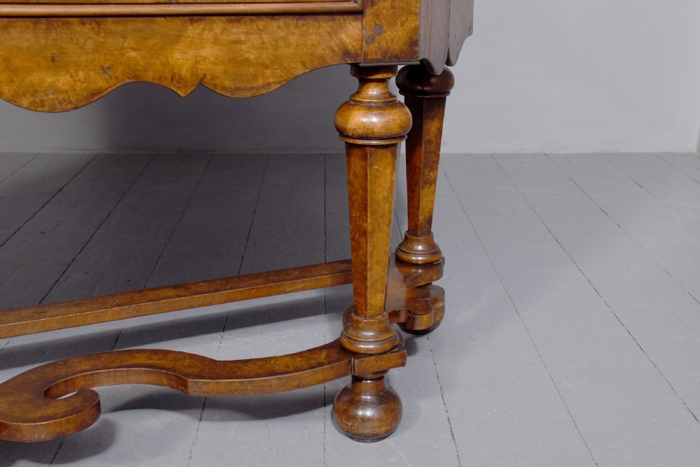 A nineteenth-century Dutch burr walnut display cabinet featuring canted glazed sides, an arched cresting cornice, two lower drawers, and turned legs connected by a shaped stretcher. View V