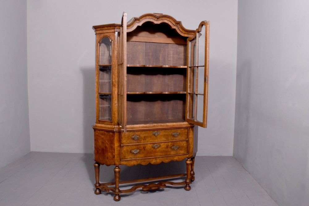 A nineteenth-century Dutch burr walnut display cabinet featuring canted glazed sides, an arched cresting cornice, two lower drawers, and turned legs connected by a shaped stretcher. View IX