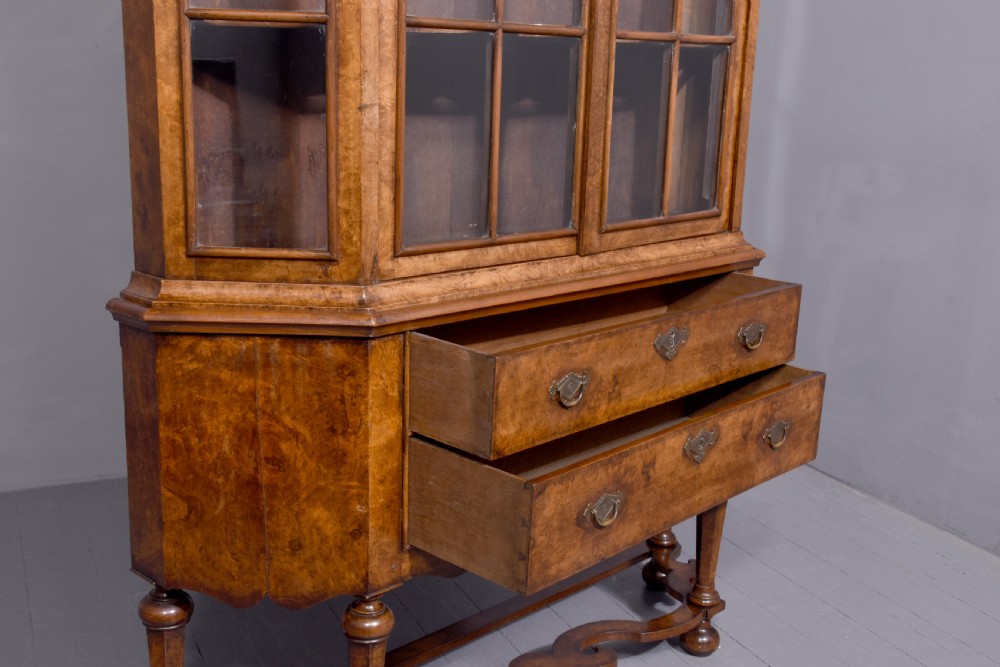 A nineteenth-century Dutch burr walnut display cabinet featuring canted glazed sides, an arched cresting cornice, two lower drawers, and turned legs connected by a shaped stretcher. View XI