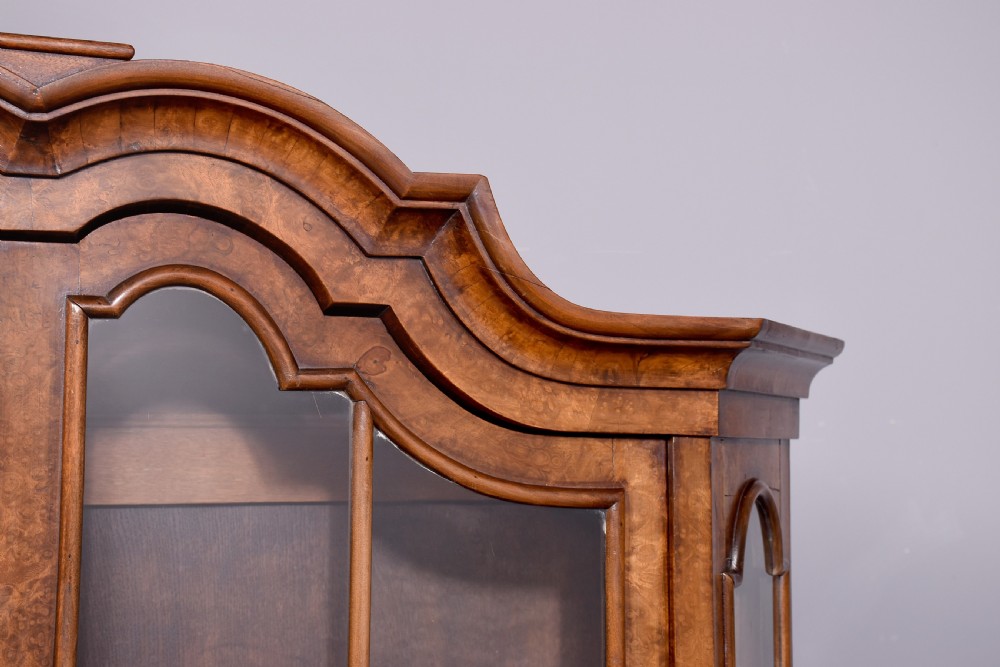 A nineteenth-century Dutch burr walnut display cabinet featuring canted glazed sides, an arched cresting cornice, two lower drawers, and turned legs connected by a shaped stretcher. View XIV