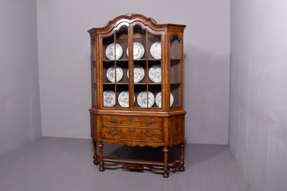 A nineteenth-century Dutch burr walnut display cabinet featuring canted glazed sides, an arched cresting cornice, two lower drawers, and turned legs connected by a shaped stretcher. View XVI