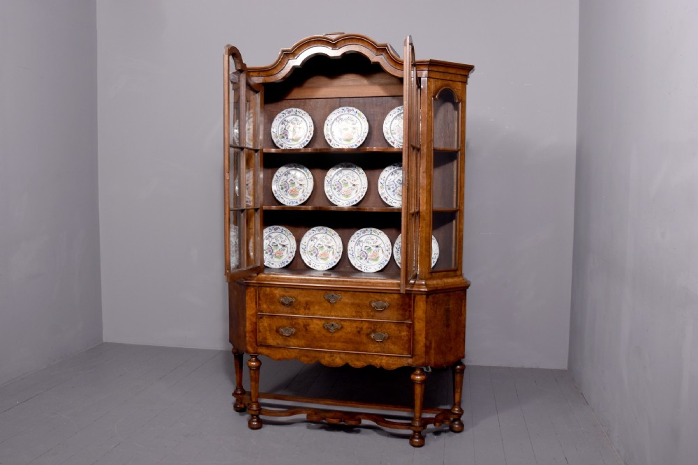A nineteenth-century Dutch burr walnut display cabinet featuring canted glazed sides, an arched cresting cornice, two lower drawers, and turned legs connected by a shaped stretcher. View XVII