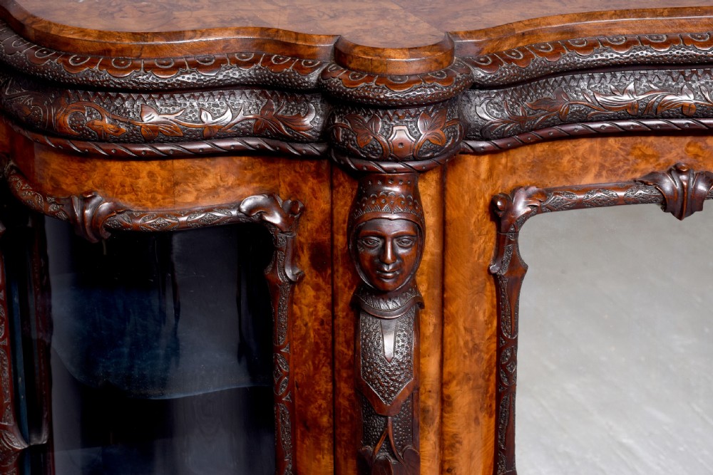 A mid-Victorian burr walnut serpentine-fronted credenza featuring carved female figure pilasters, central mirrored doors, and curved glass side display cabinets. View VIII