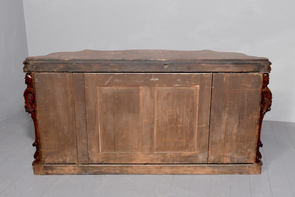 A mid-Victorian burr walnut serpentine-fronted credenza featuring carved female figure pilasters, central mirrored doors, and curved glass side display cabinets. View XV