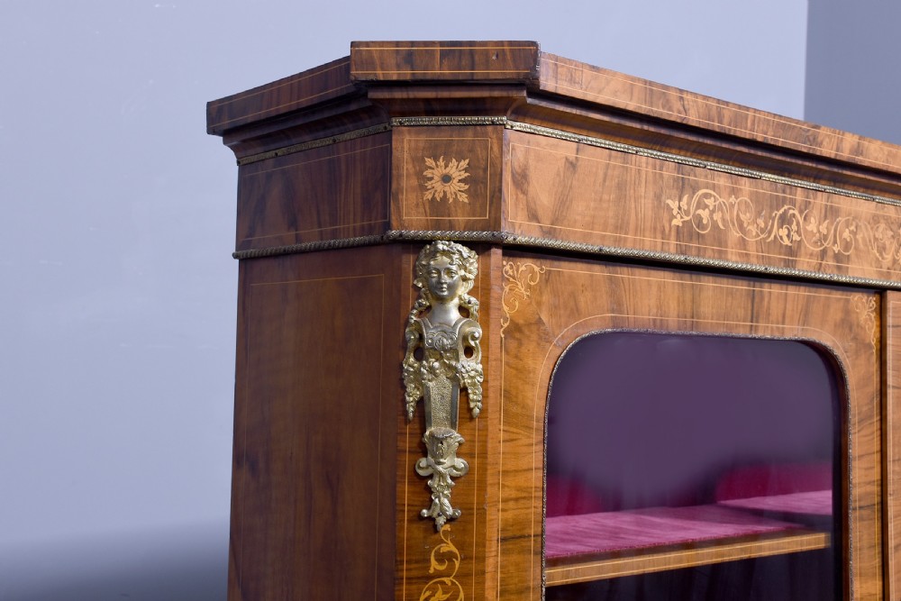 A Victorian figured walnut cabinet featuring twin glazed doors, intricate marquetry floral inlay along the frieze, gilt bronze mounts, and a red fabric-lined interior with three shelves. View VII