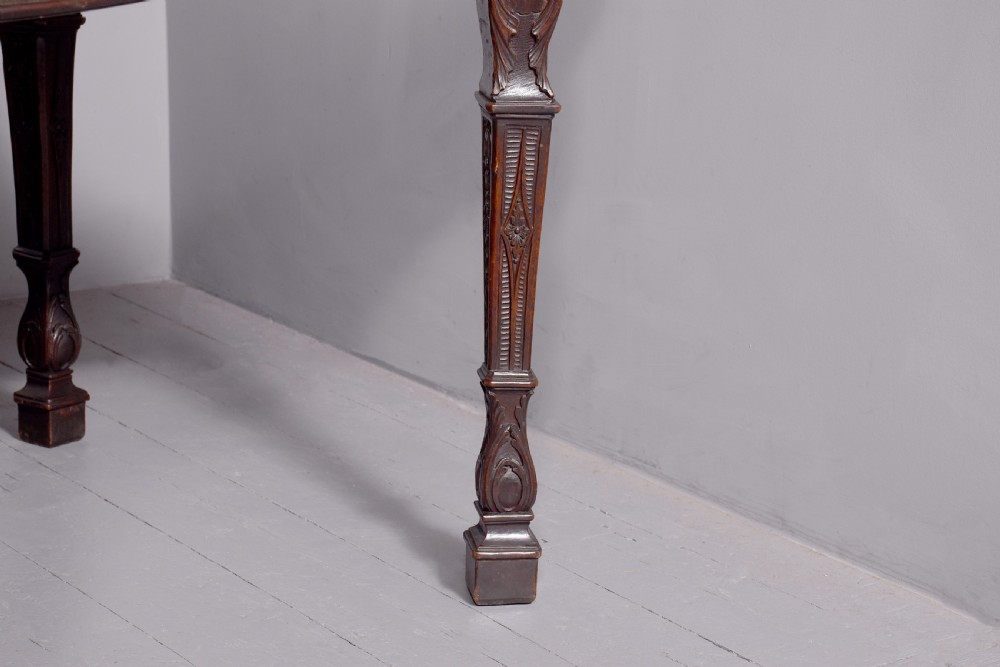 A wide George III dark mahogany serving table supported by six carved legs with intricate drapery swags running across the front frieze. View II