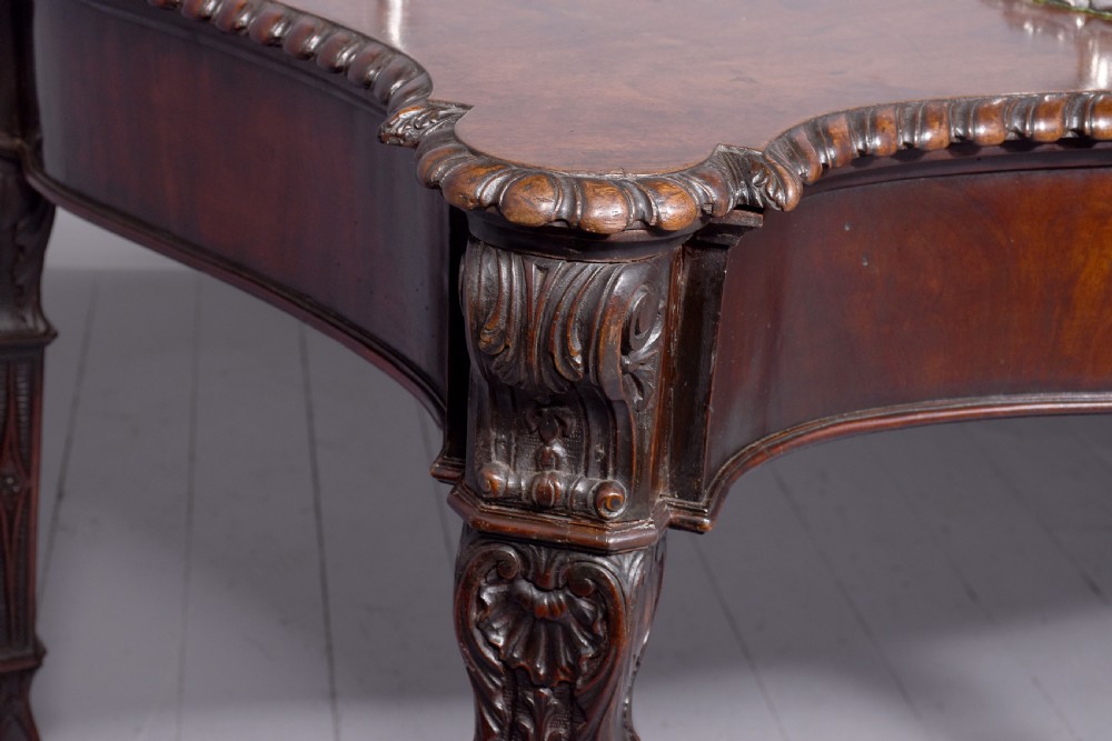 A wide George III dark mahogany serving table supported by six carved legs with intricate drapery swags running across the front frieze. View V