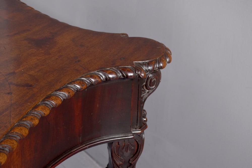 A wide George III dark mahogany serving table supported by six carved legs with intricate drapery swags running across the front frieze. View VI