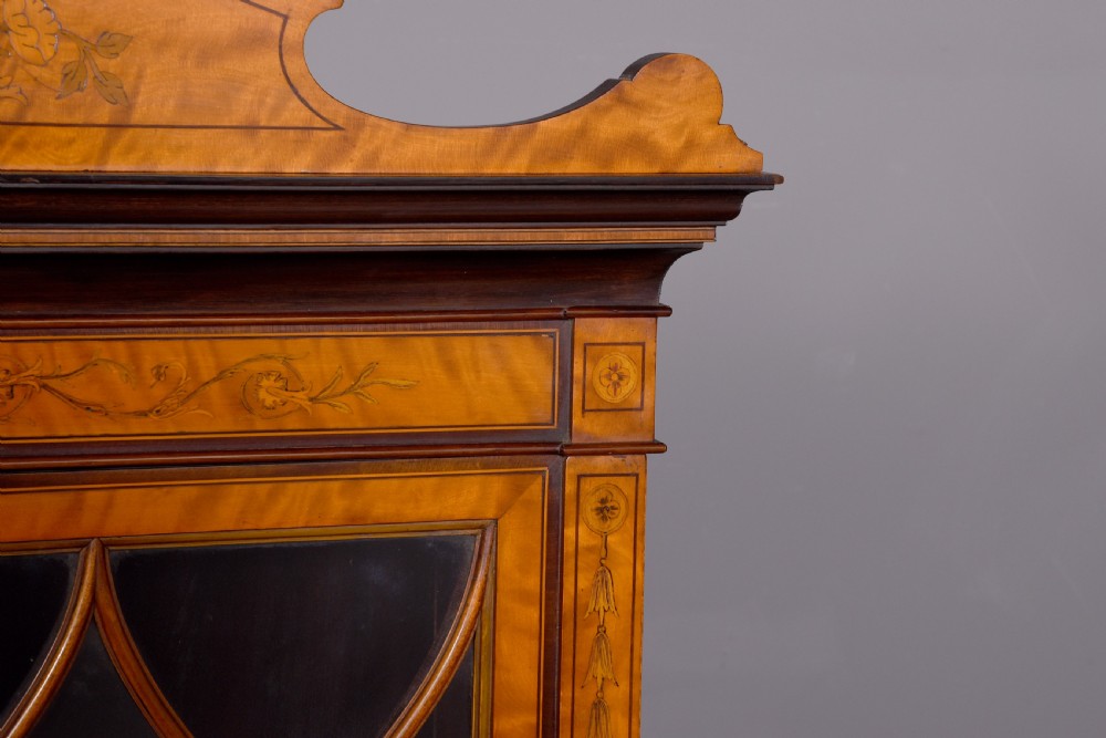 An antique satinwood secretaire bookcase featuring glazed upper doors with astragal tracery, detailed floral marquetry inlays, and an arched pediment. View IV