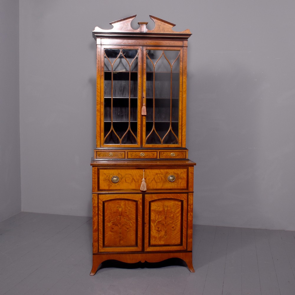 An antique satinwood secretaire bookcase featuring glazed upper doors with astragal tracery, detailed floral marquetry inlays, and an arched pediment. View VI