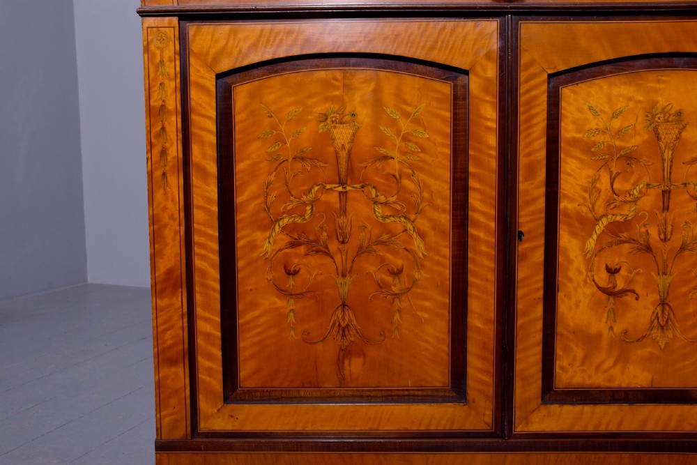 An antique satinwood secretaire bookcase featuring glazed upper doors with astragal tracery, detailed floral marquetry inlays, and an arched pediment. View IX