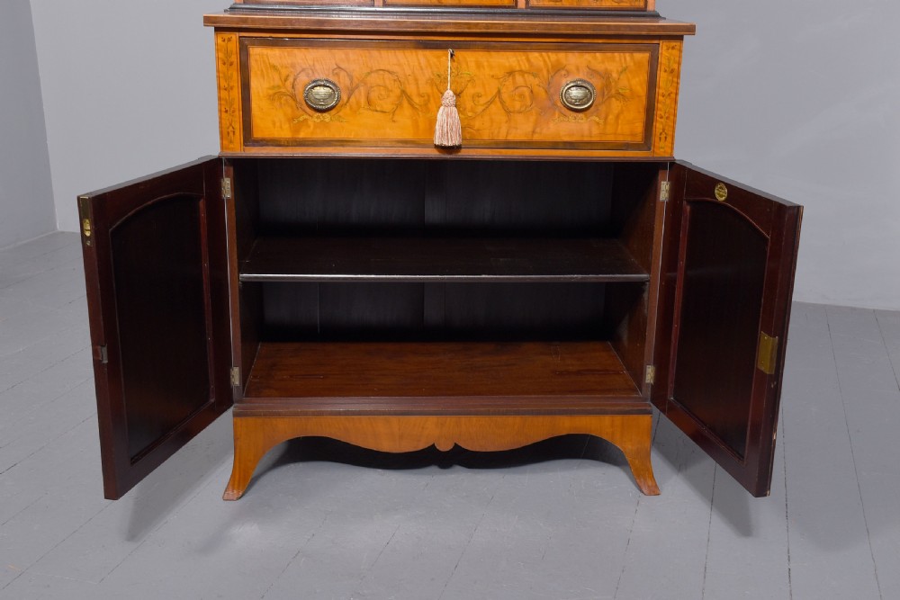 An antique satinwood secretaire bookcase featuring glazed upper doors with astragal tracery, detailed floral marquetry inlays, and an arched pediment. View XII