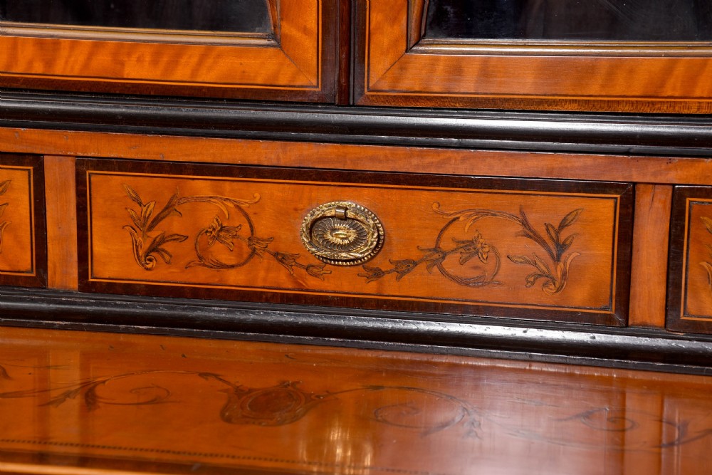 An antique satinwood secretaire bookcase featuring glazed upper doors with astragal tracery, detailed floral marquetry inlays, and an arched pediment. View XVII