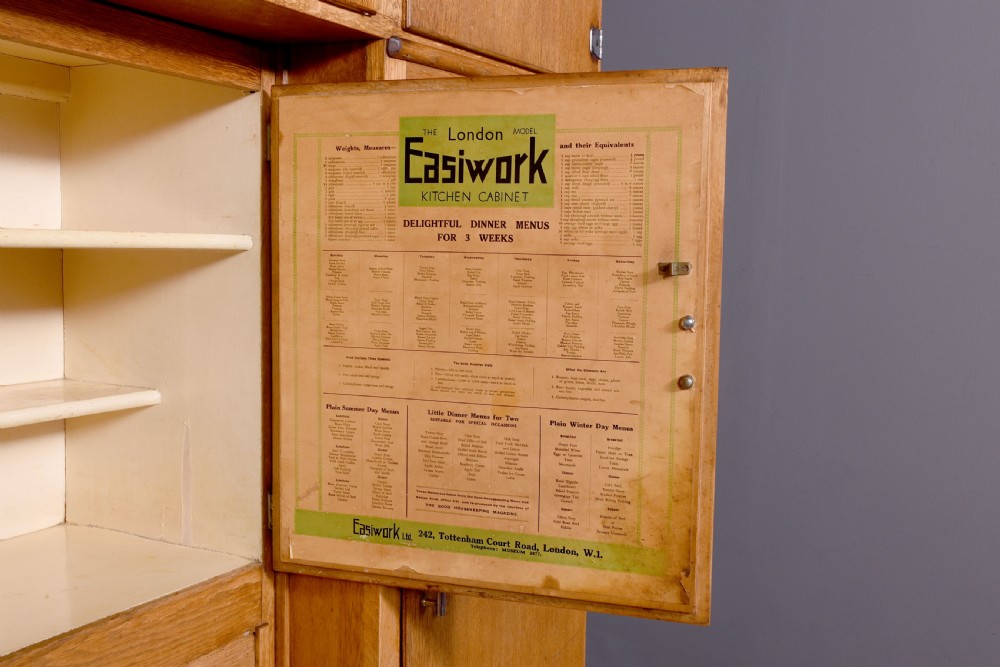 A tall oak Easiwork kitchen cabinet featuring multiple storage cupboards, drawers, an integrated enamel work surface, and an internal flour sifter mechanism. View XII