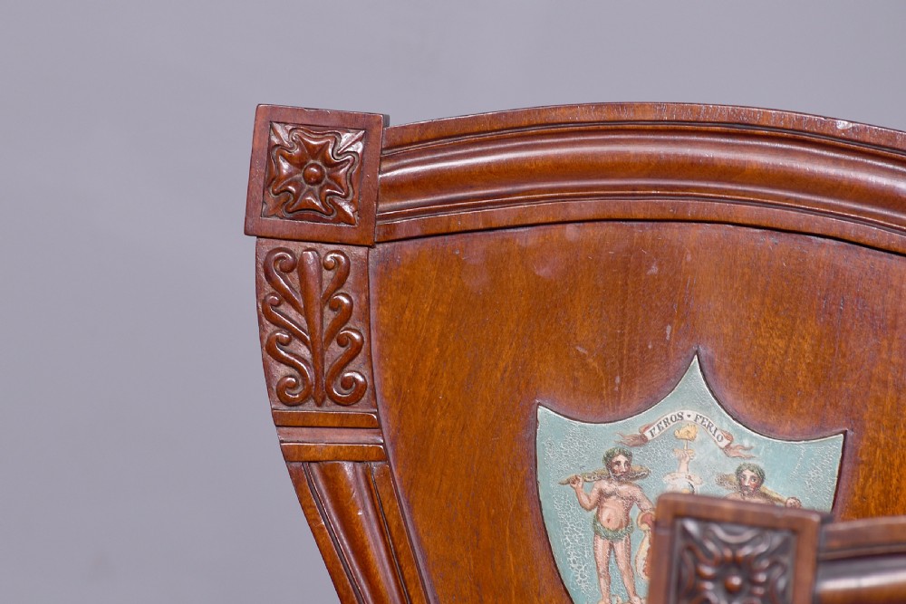 A set of five George IV mahogany hall chairs featuring carved backrest scrolls, turned fluted front legs, and hand-painted heraldic crest shields. View III