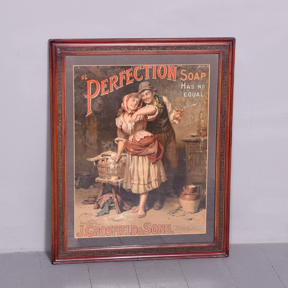 A framed Edwardian pictorial advertising poster for Perfection Soap depicting a man and woman in a rustic setting within a moulded dark wood frame.