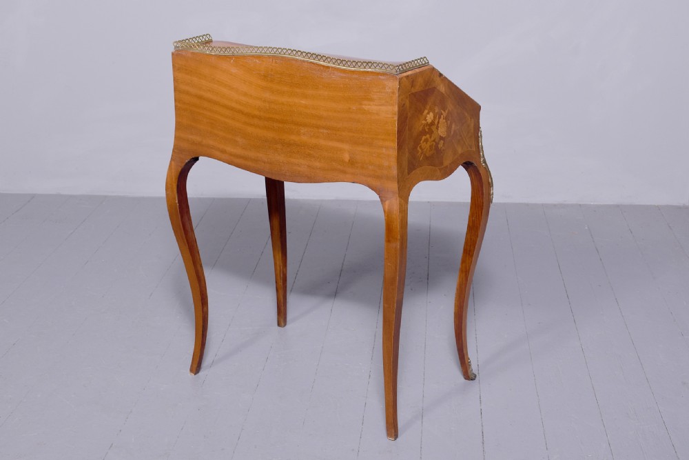 A small French Louis XV style slope-front writing desk featuring floral marquetry inlays, cabriole legs with brass mounts, and a brass gallery rail. View III