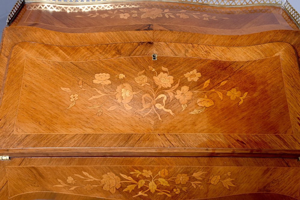 A small French Louis XV style slope-front writing desk featuring floral marquetry inlays, cabriole legs with brass mounts, and a brass gallery rail. View IV